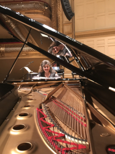 Pianist Christina Dietrich sitting at the keyboard of a grand piano.
