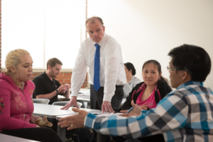small business employees sit around a table. An istructor teaches them supervisory skills.