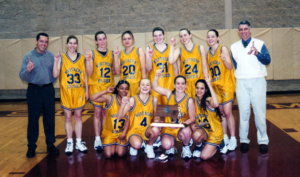 The members of the 2000-01 women's basketball team and their coaches pose for a celebratory photo.