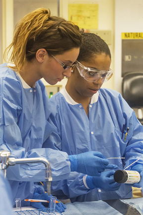 photo of two individuals dressed in PPE in a lab setting