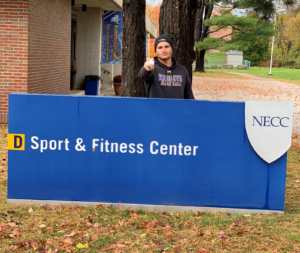 Student Athlete Mike Stellato standng in front of the NECC Sport a nd Fitness Center sign.