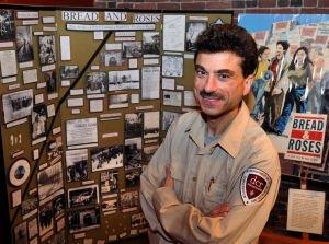 man with mustache in front of photo and text posterboard display.
