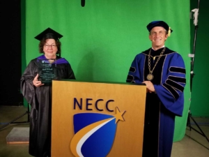 Man and woman holding award in academic regalia.